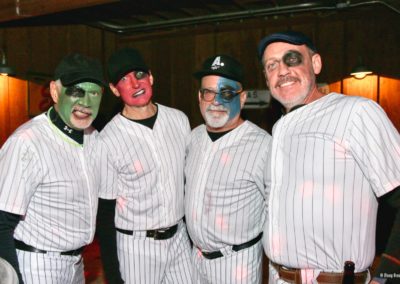 Four people dressed in baseball outfits pose for Dunes Resorts Halloween 2021 party.
