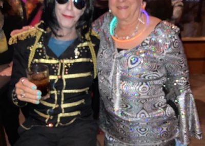 Two people dressed in disco costumes smile and pose for Dunes Resorts Halloween 2021 Party.