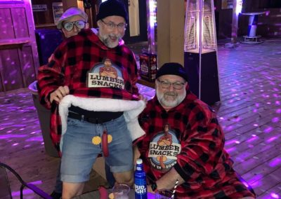 Two people dressed as cozy lumberjacks and one person wearing Jaxon hat pose for Dunes Resorts Halloween 2021 Party