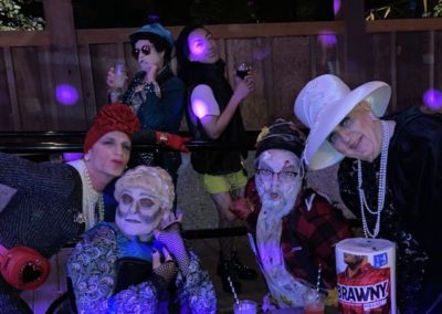 Group of people outside in the dark under purple party lights dance and pose for Dunes Resorts Halloween 2021 Party.