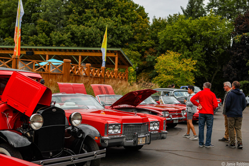 A line of red vintage cars is parked with their engines on display at The Dunes Resort.