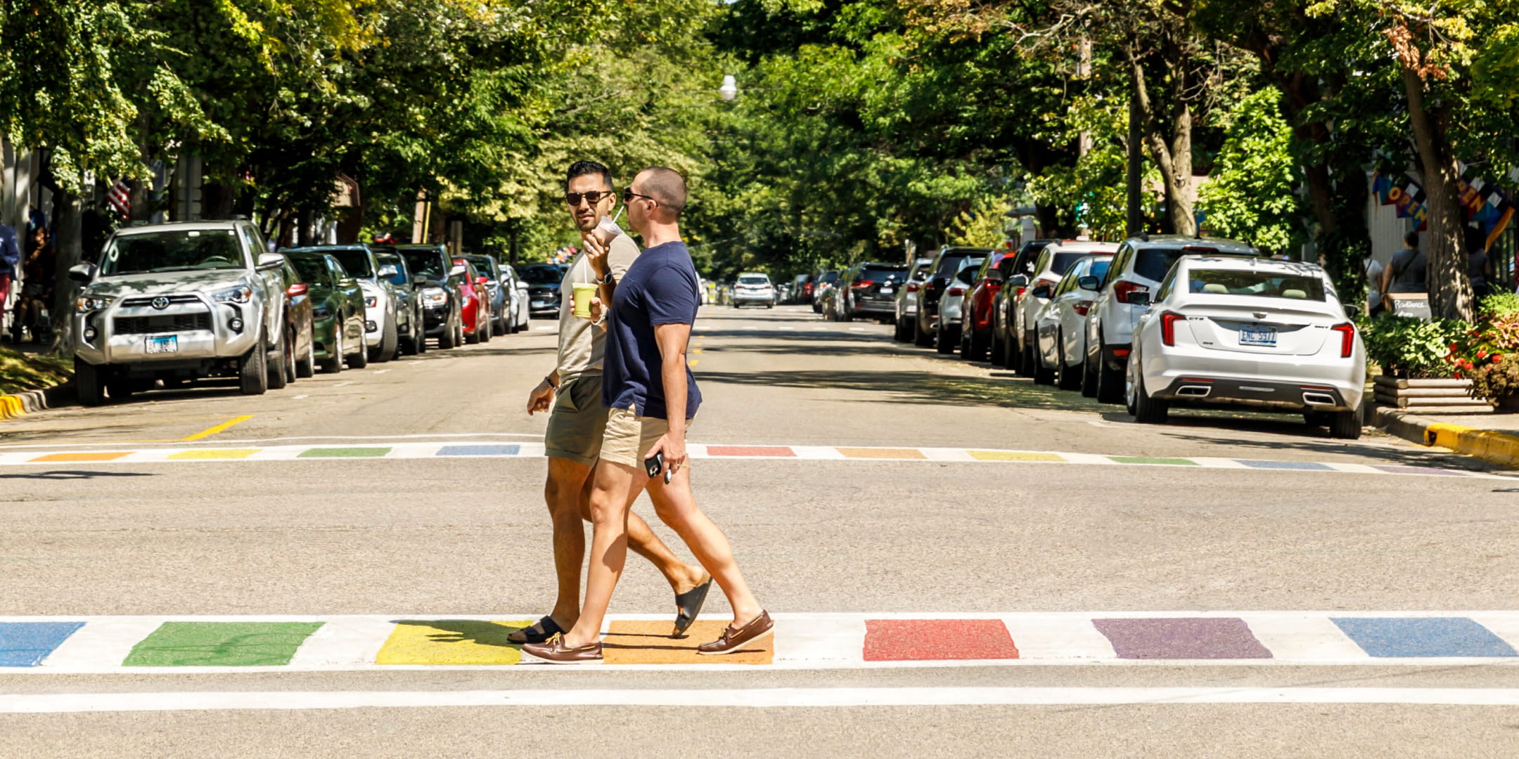 Two men walking across a painted rainbow sidewalk in downtown Saugatuck.