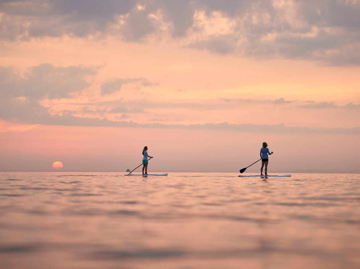 Paddleboarders enjoy a serene sunset over Lake Michigan, capturing the essence of tranquility.